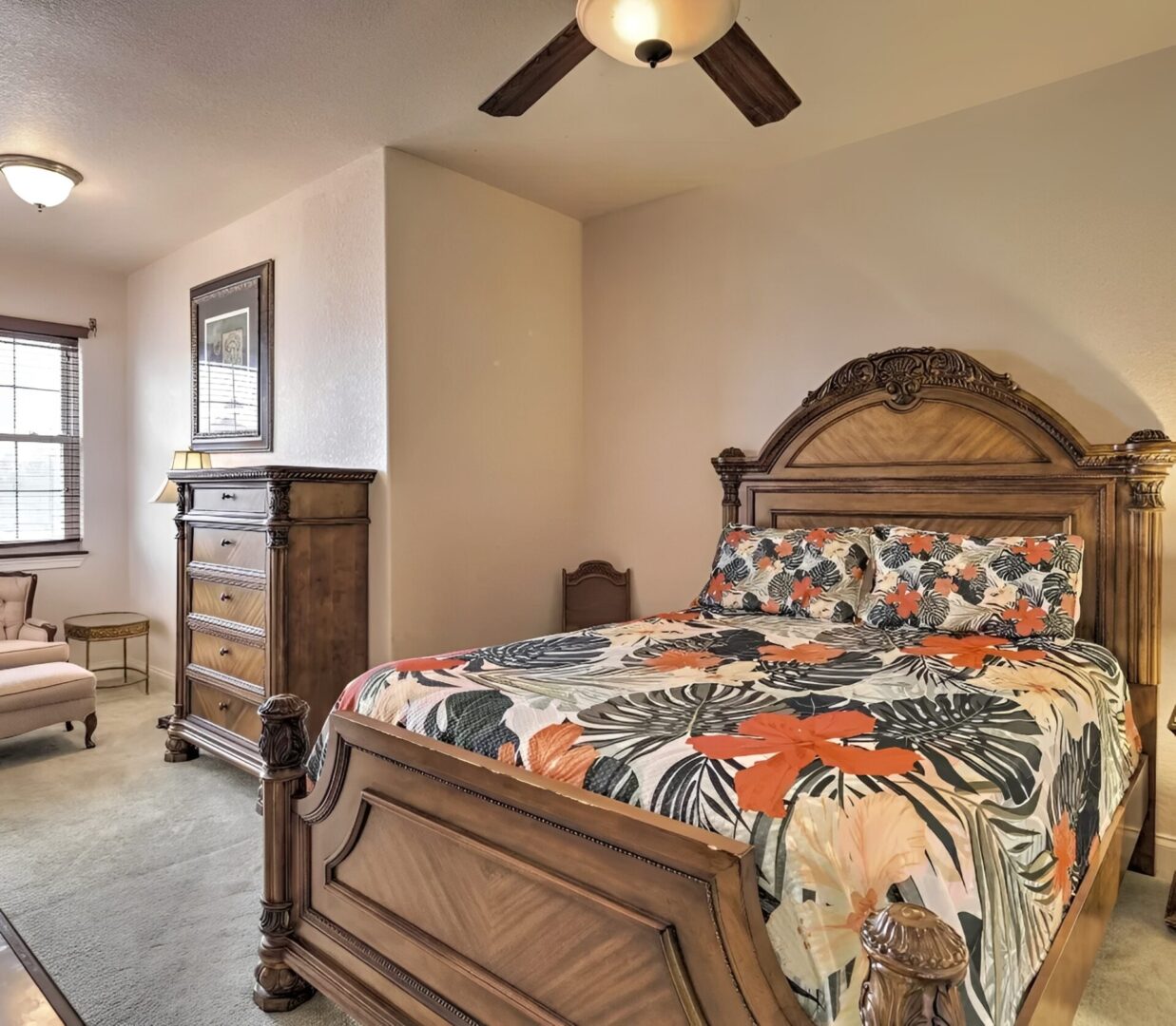 Bedroom with floral bedspread and wooden furniture.